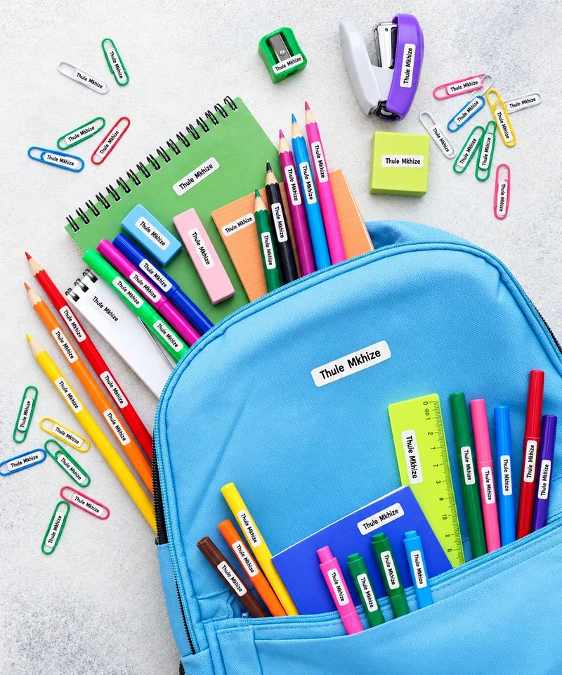 Blue backpack spilling pencils, pens, a notebook, a stapler and paper clips, every item with a Thule Mkhize name label