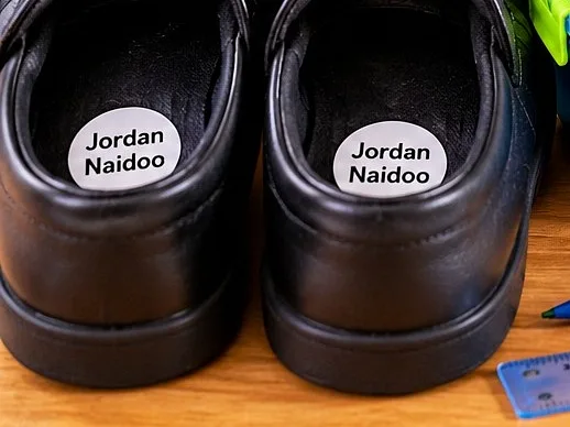 Black school shoes with round Jordan Naidoo name labels on the insoles