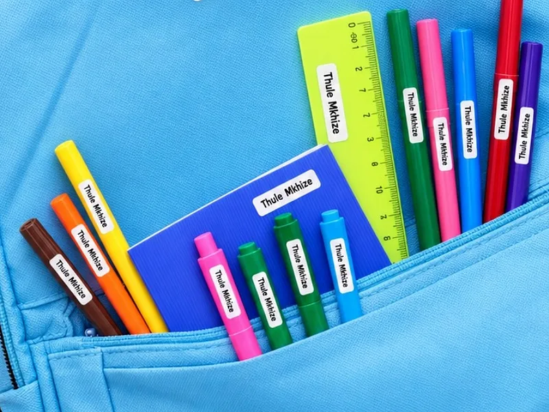Coloured pencils, crayons and a ruler in a backpack pocket, each with a small Thule Mkhize name label